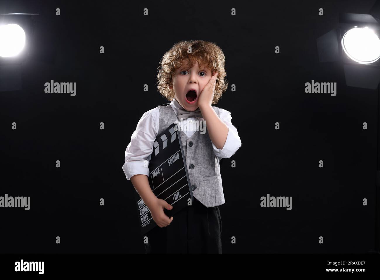 Emotionaler Junge mit Klapperbrett auf der Bühne. Kleiner Schauspieler Stockfoto