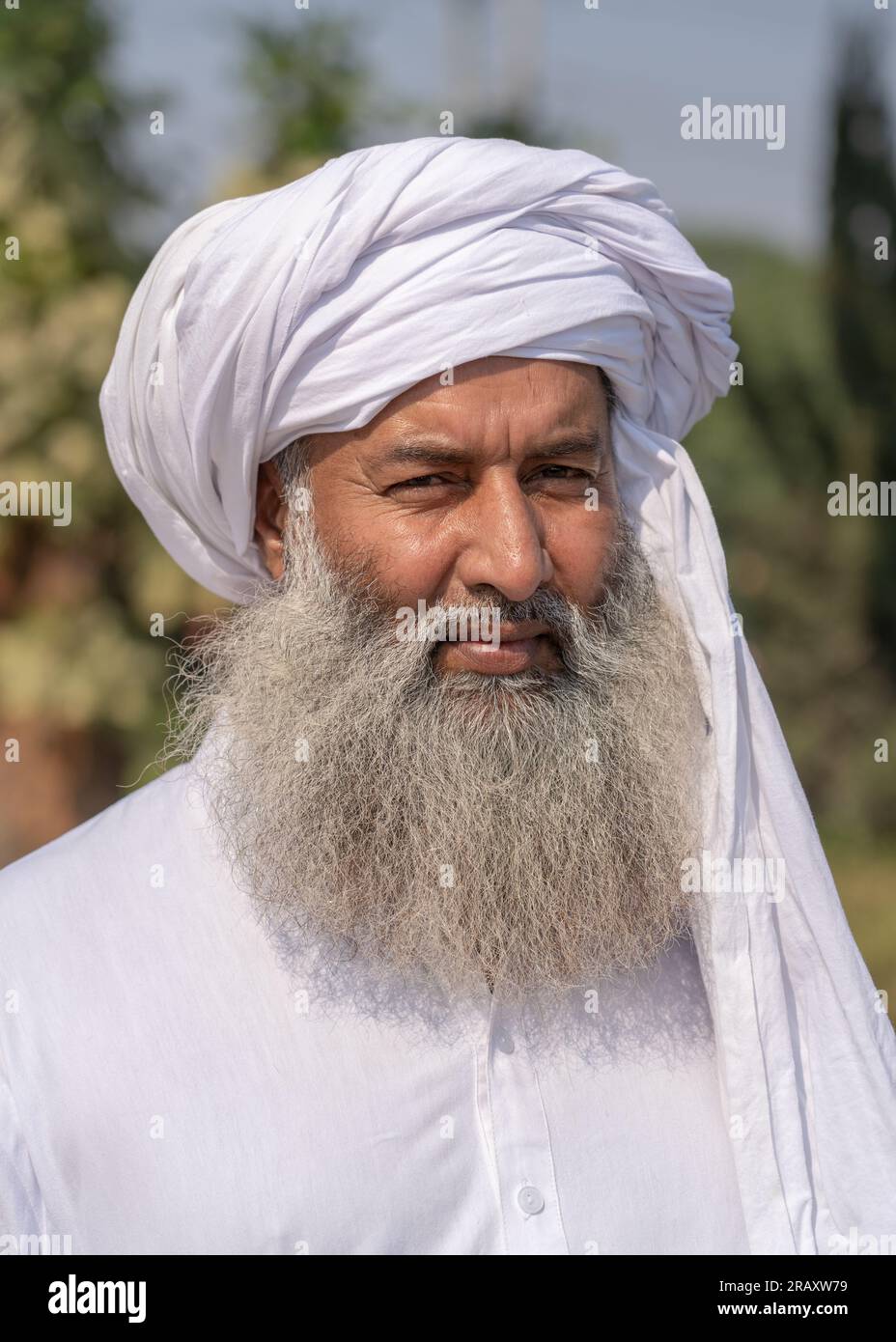 Außenporträt eines bärtigen Mannes mittleren Alters mit traditionellem weißen Kleid und Turban Stockfoto