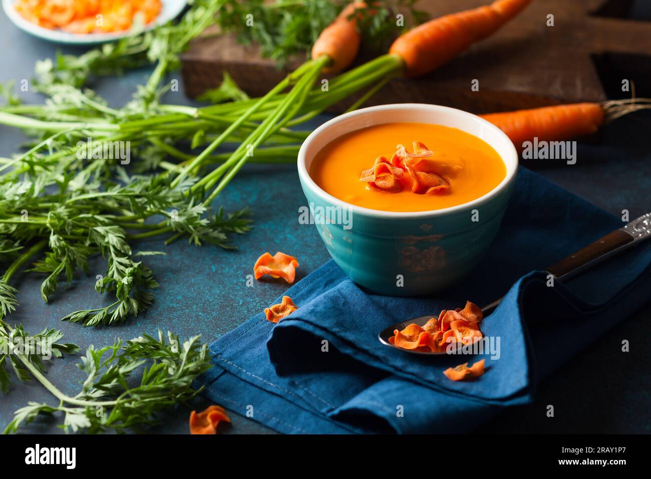 Cremige Karotten- und Kürbissuppe mit Karottenchips in einer blauen Schüssel. Scharfe Sahne-Gemüse-Suppe. Stockfoto