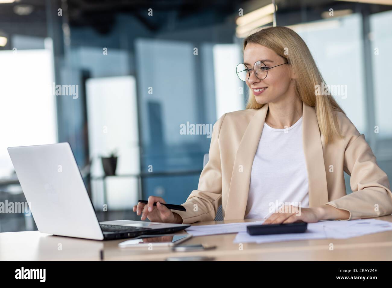 Porträt einer lächelnden jungen Geschäftsfrau, Bankangestellten, Managerin, die im Büro mit Dokumenten und Laptop arbeitet. Stockfoto