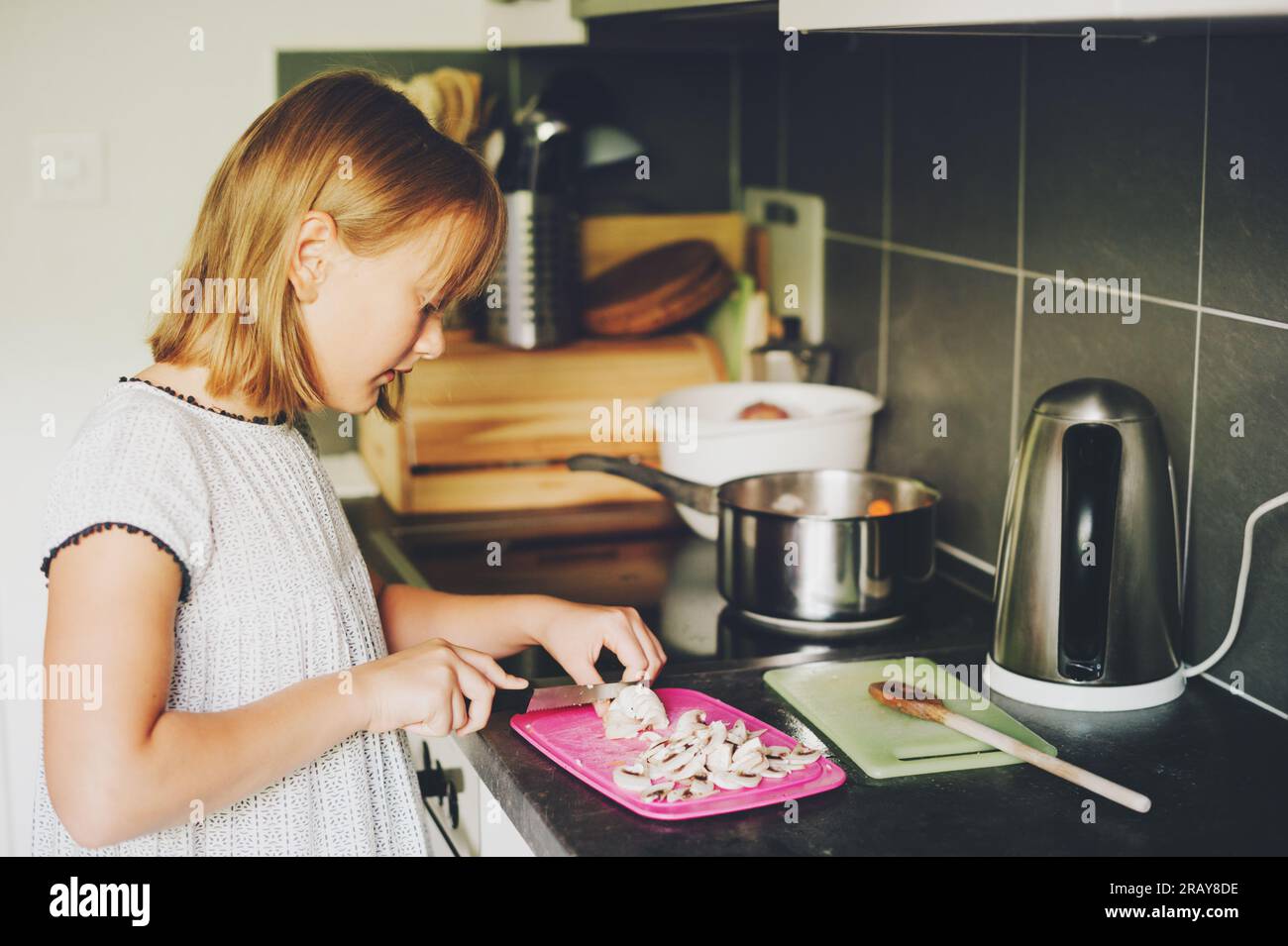 Süßes kleines Mädchen, das Gemüse für die Familie kocht, Kind, das in der Küche hilft Stockfoto