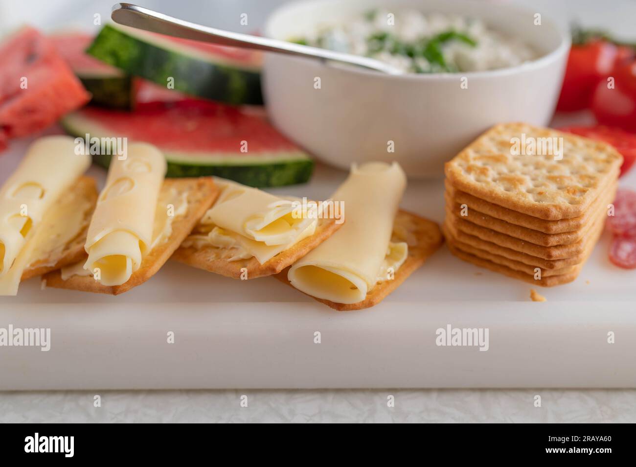 Vorspeise mit Käse und Crackern auf einem weißen Schneidebrett Stockfoto