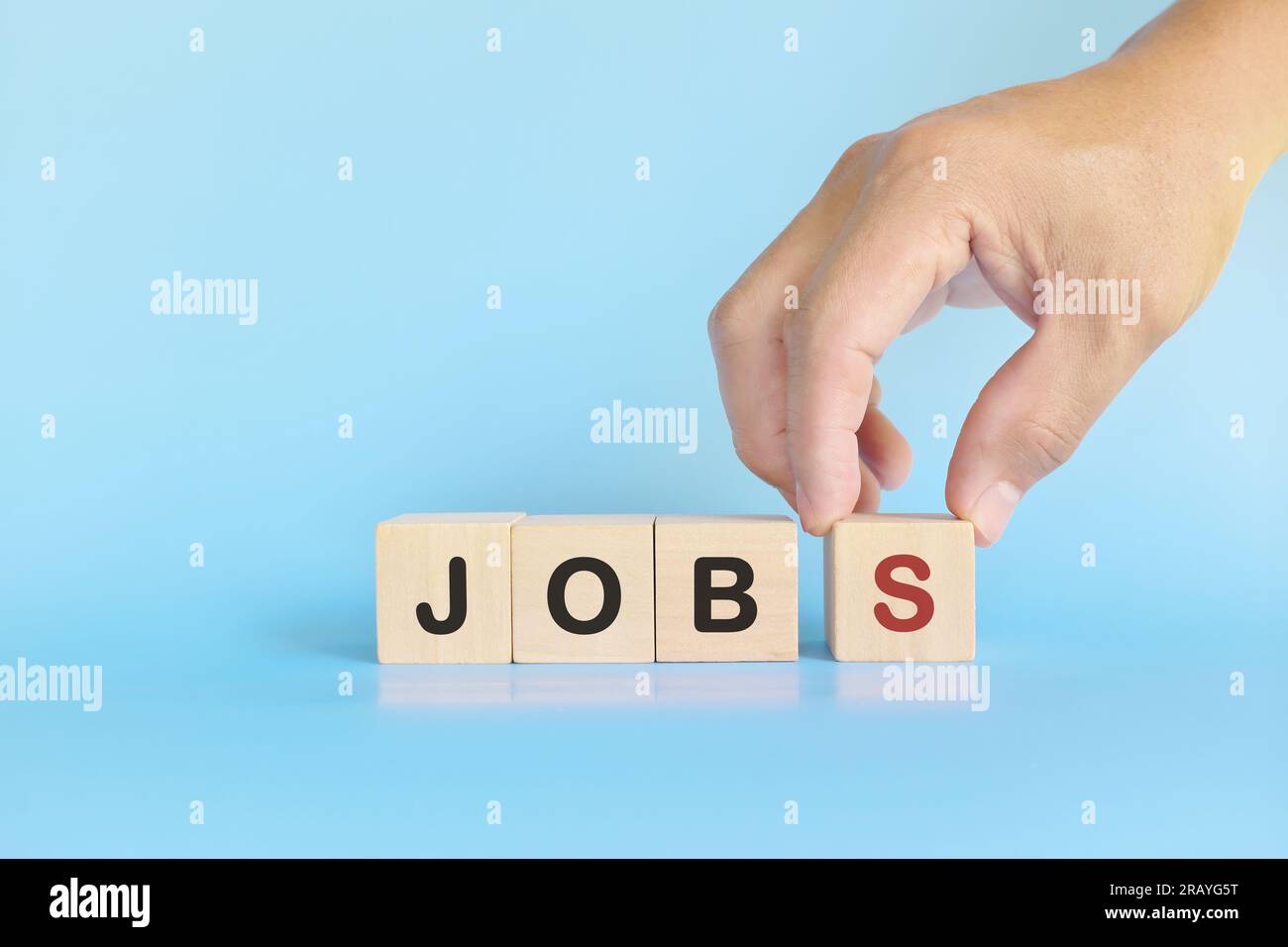 Konzept der Schaffung von Arbeitsplätzen und der Stabilität. Menschliches Stapeln von Holzblöcken mit der Hand. Stockfoto