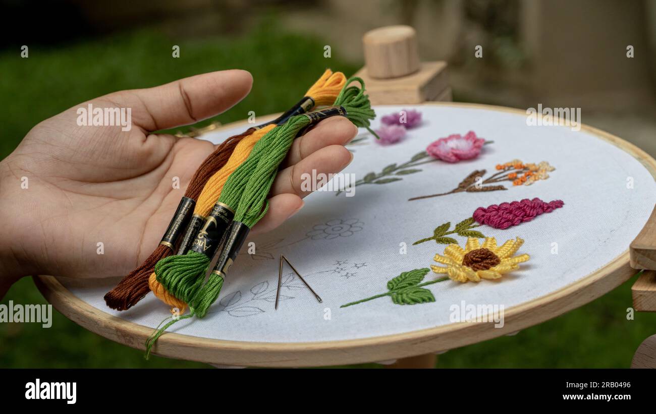 Bestickte Seidenfäden und genähte Blumen auf einem Standbügel Stockfoto