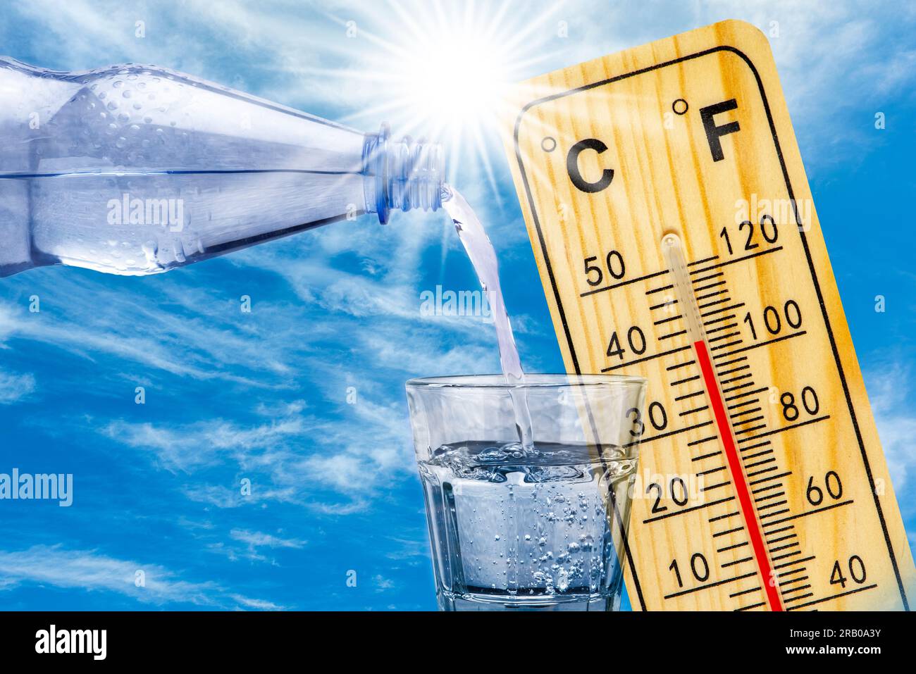 Thermometer zeigt hohe Temperaturen in der Sommerhitze und Flasche mit Wasser mit Trinkglas an Stockfoto