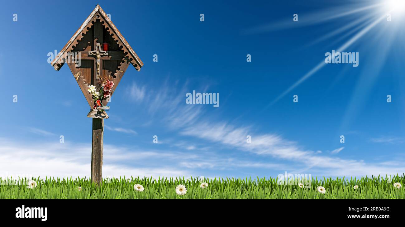 Kleiner Votivschrein aus Holz (Äedikula) mit Jesus Christus gekreuzigt auf einer grünen Wiese vor einem klaren blauen Himmel mit Wolken, Sonnenstrahlen und Kopierraum. Tre Stockfoto