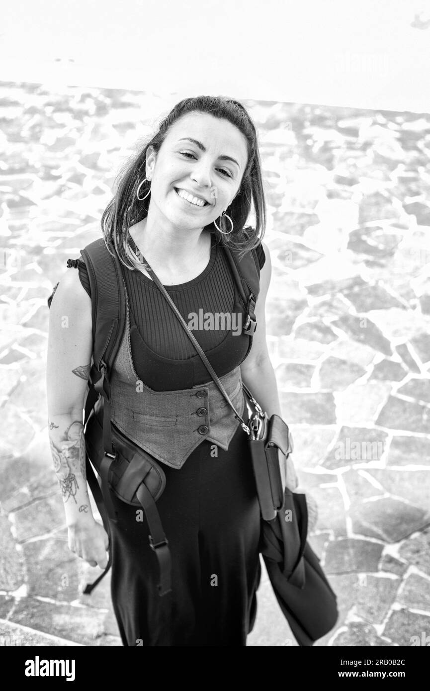 Lächelndes Mädchen, mit tätowiertem Arm und einem Rucksack auf der Schulter. Glücklicher Tourist Stockfoto