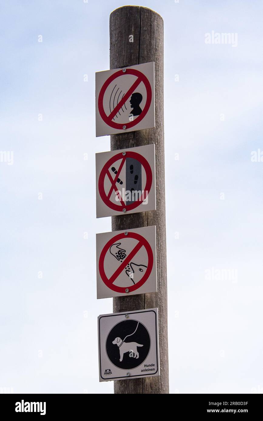 Füttern Sie die Delfine nicht auf dem GOLDSTEIG Trail? Die Piktogramme auf einem Wegweiser mit verhaltensbezogenen Ratschlägen lassen einige Fragen offen. Stockfoto