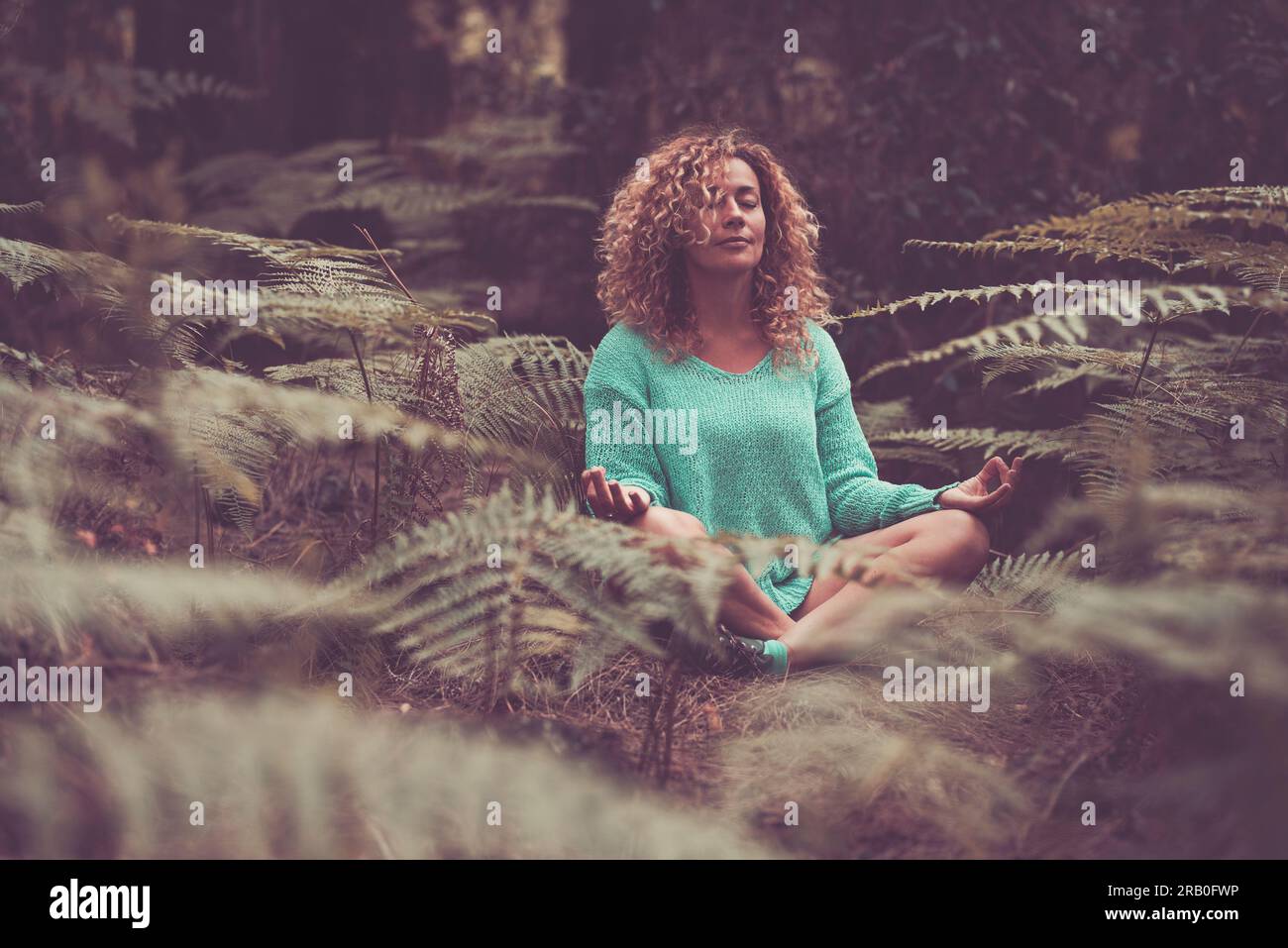 Lebensgleichgewicht Naturkontakt Gefühl der Ruhe Frau meditiert in Lotus-Yoga-Haltung. Glück und Entspannung im Wald mit tropischem Laub. Gäste Outdoor Entspannung Stockfoto