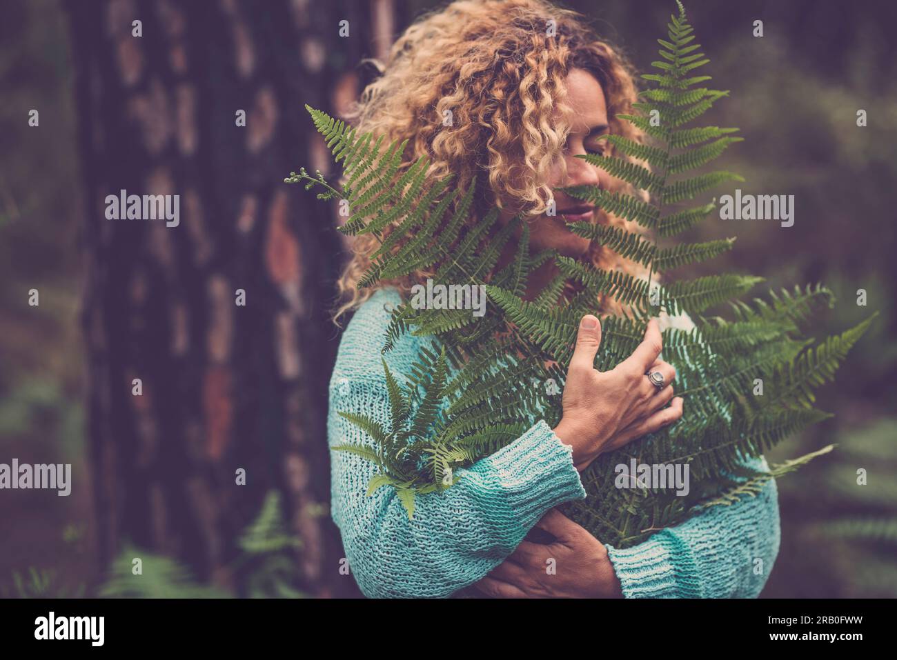 Eine Frau umarmt große tropische Blätter. Naturliebhaber und Lebensstil der Umwelt. Die Menschen fühlen sich mit der Natur verbunden. Glückliches Leben. Bild des Konzepts für den Schutz von Waldgrünen Hölzern. Balance Stockfoto