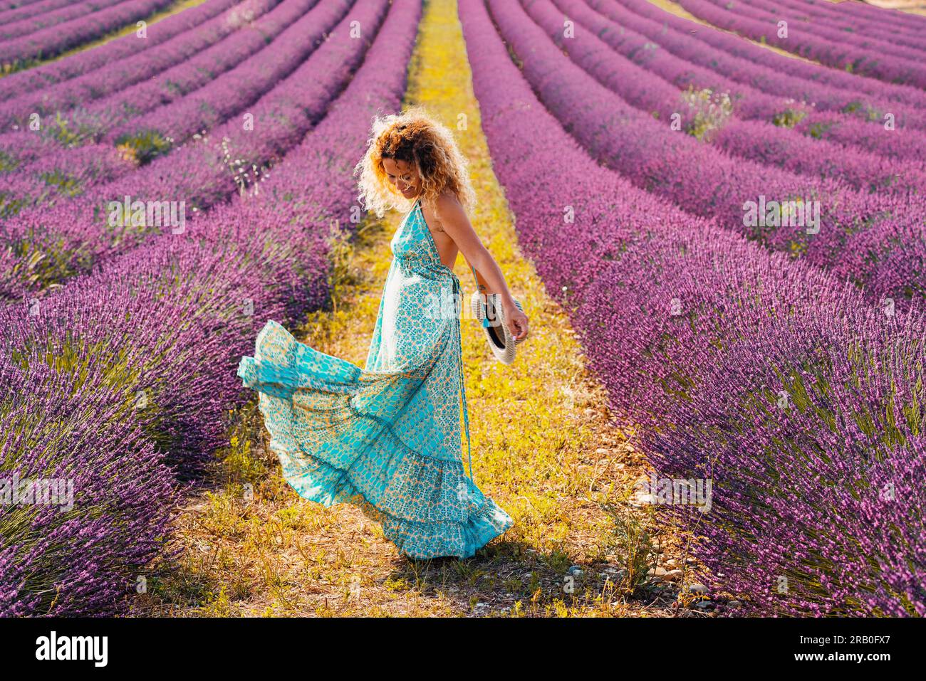 Glückliche Touristin mit Modekleid, die auf dem Lavendelfeld tanzt. Farbenreiseziel Menschen und Glück. Sommerurlaub und Freizeitaktivitäten im Freien. TourismusLifestyle für Reisende Stockfoto