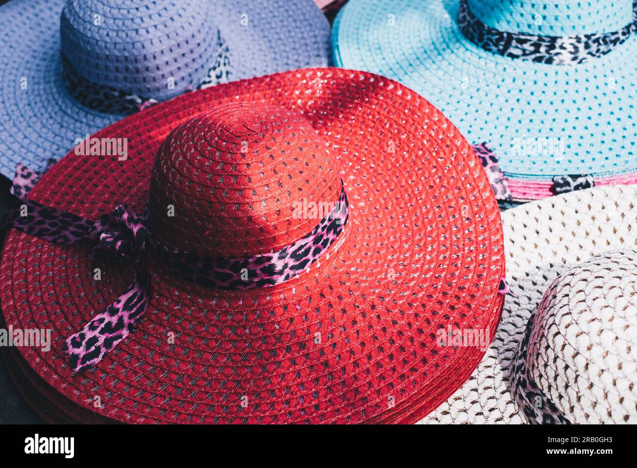 Farbenfroher UV-Schutz für Damen mit breitem Schirm und atmungsaktivem Strohhut mit Leopardenbogenknoten zum Schutz vor Sonnenstrahlen. Selektiver Fokus. Stockfoto