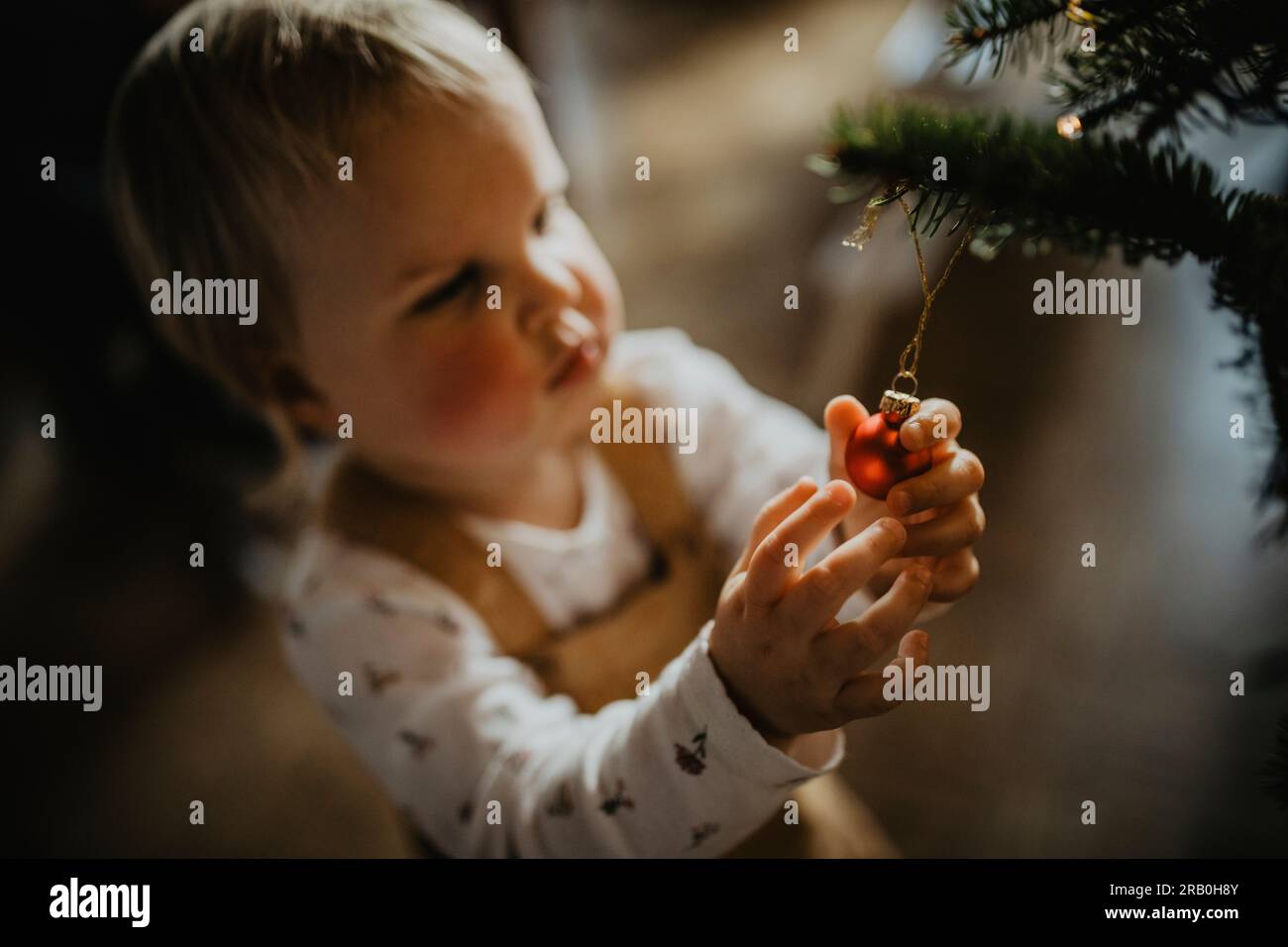 Das kleine Mädchen hilft beim Dekorieren des Weihnachtsbaums Stockfoto