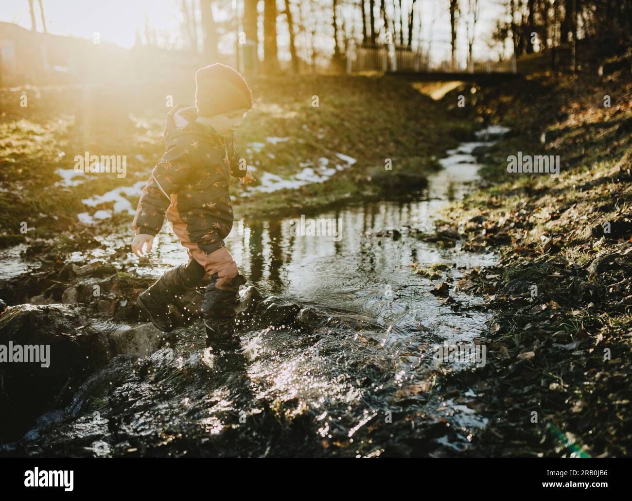 Ein Junge, der durch einen Fluss im Wald rennt Stockfoto