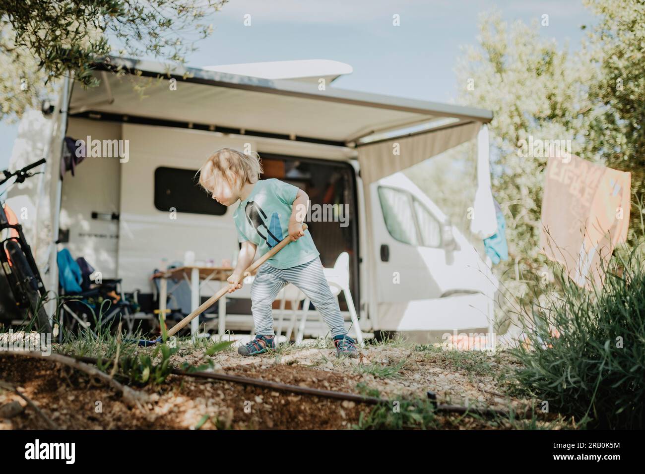 Ein kleines Mädchen, das vor einem Wohnwagen auf einem Campingplatz spielt Stockfoto