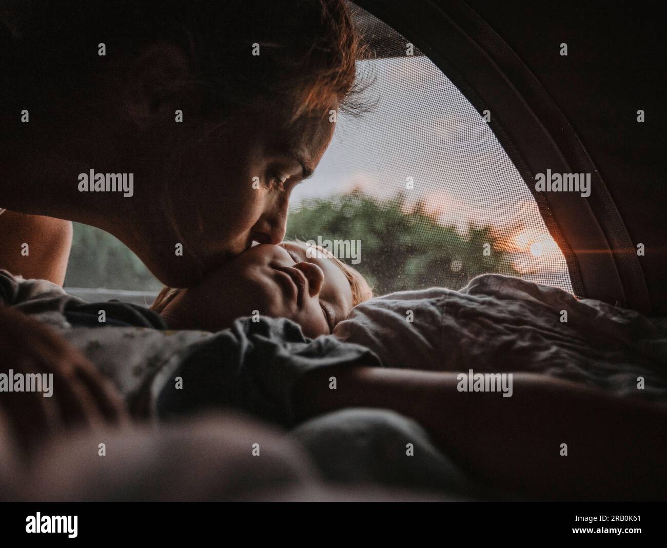 Mutter küsst ihren schlafenden Sohn im Wohnmobil Stockfoto