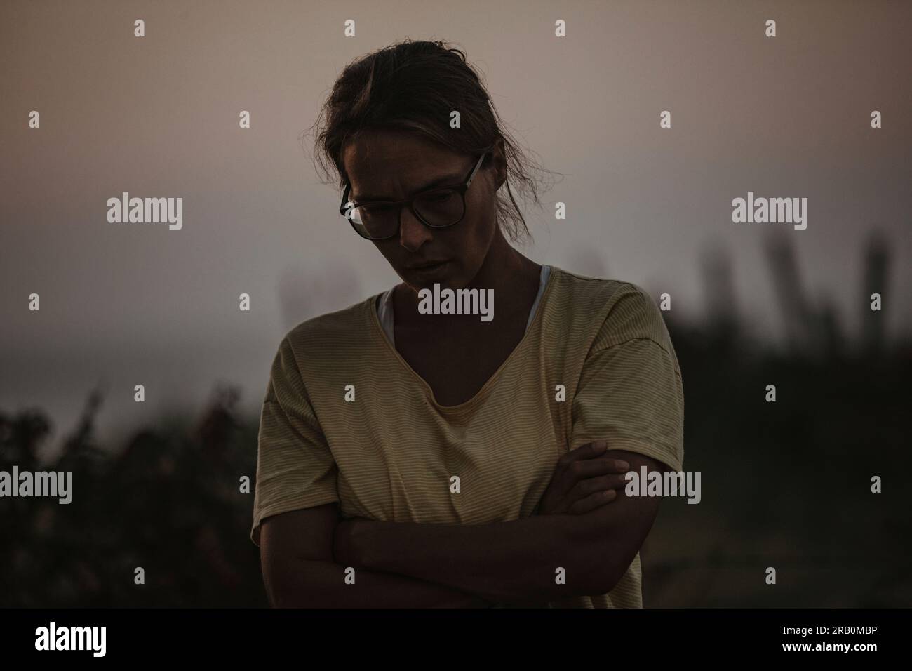 Frau mit zusammengefalteten Armen und traurigem Blick Stockfoto