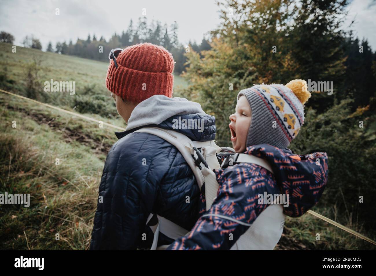 Mutter läuft in der Natur mit Tochter auf dem Rücken Stockfoto