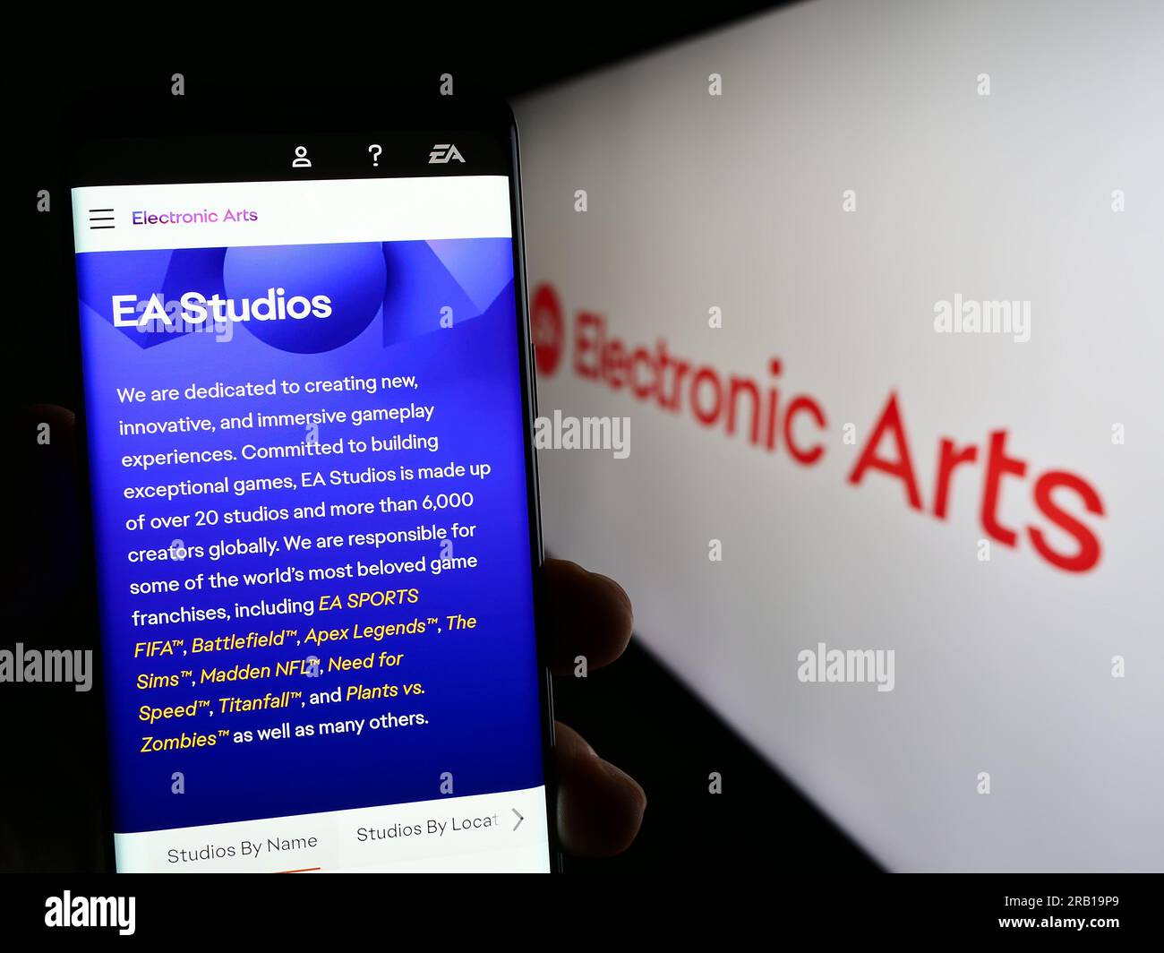 Person, die ein Mobiltelefon mit der Webseite des Videospielunternehmens Electronic Arts Inc. Besitzt (EA) auf dem Bildschirm mit Logo. Konzentrieren Sie sich auf die Mitte des Telefondisplays. Stockfoto