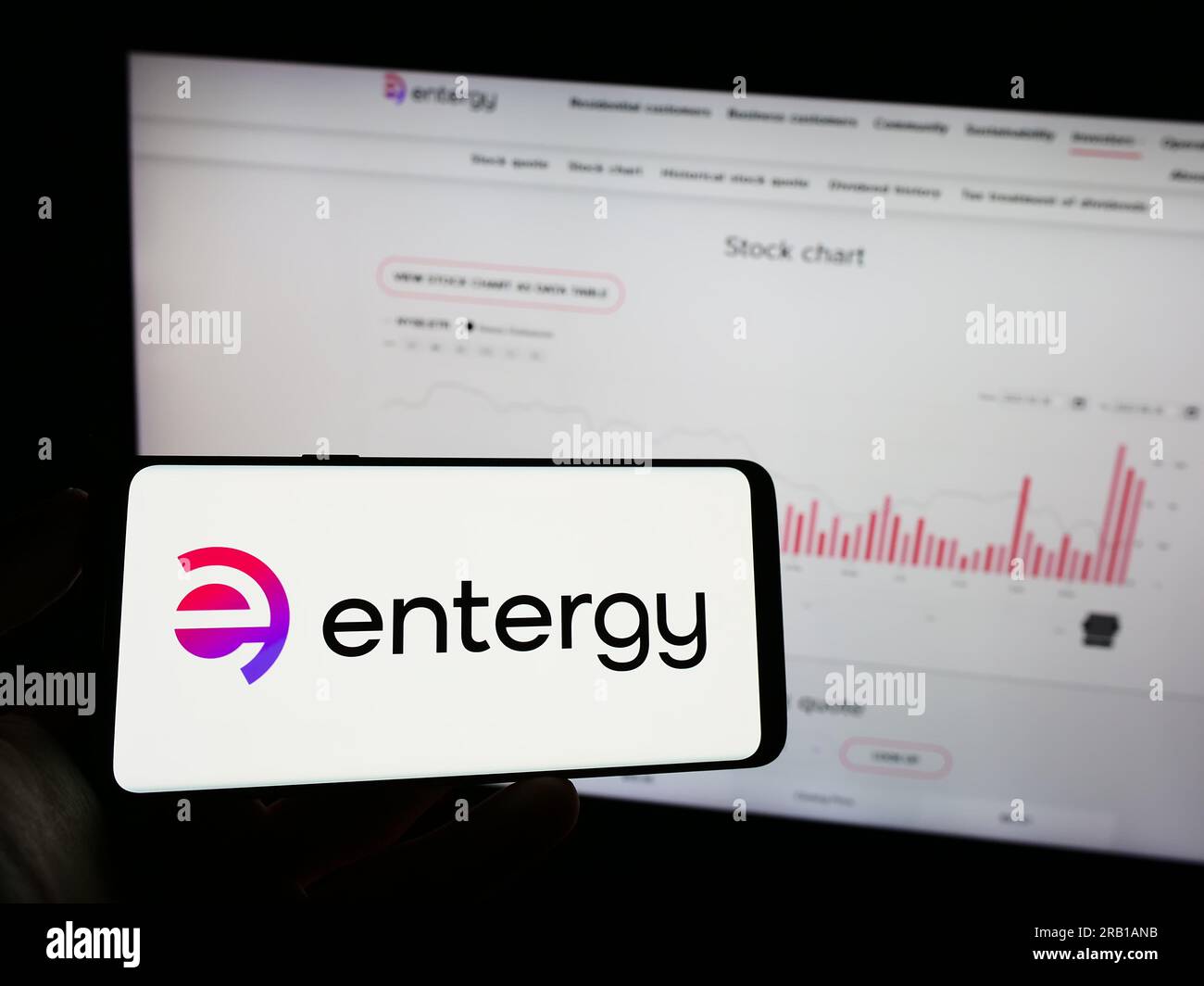 Person, die ein Mobiltelefon mit dem Logo des amerikanischen Energieunternehmens Entergy Corporation auf dem Bildschirm vor der Webseite hält. Konzentrieren Sie sich auf das Display des Telefons. Stockfoto