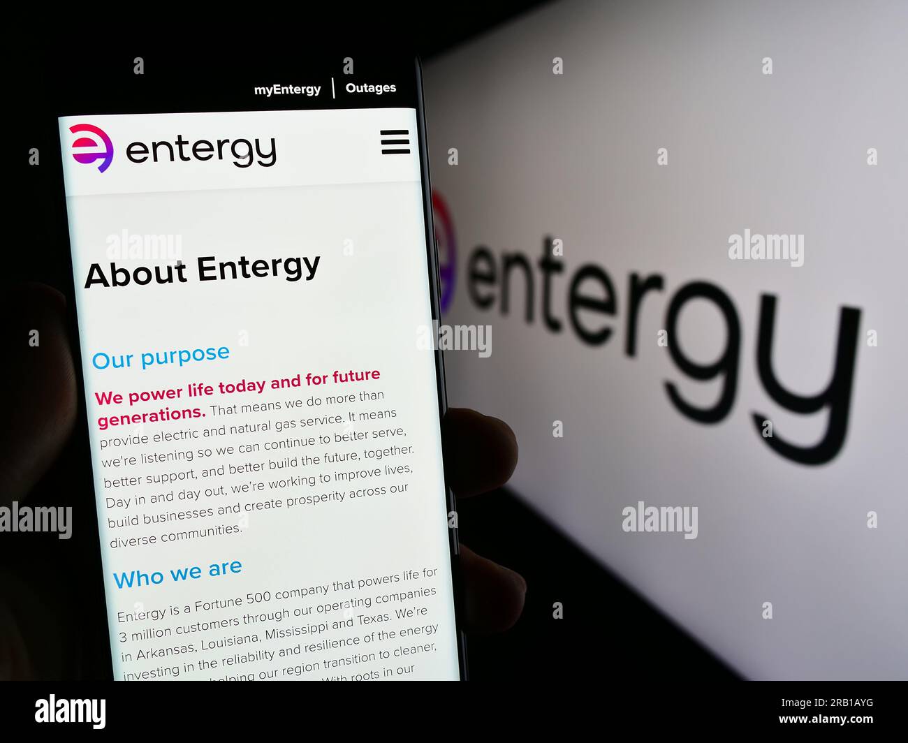 Person, die ein Mobiltelefon mit einer Webseite des US-Energieunternehmens Entergy Corporation auf dem Bildschirm vor dem Logo hält. Konzentrieren Sie sich auf die Mitte des Telefondisplays. Stockfoto