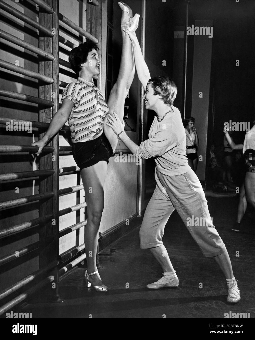 New York, New York: 30. September, 1955. Juni Taylor streckt sich persönlich eine ihrer Tänzer aus, damit sie für die nächste Nummer locker und locker ist. Stockfoto