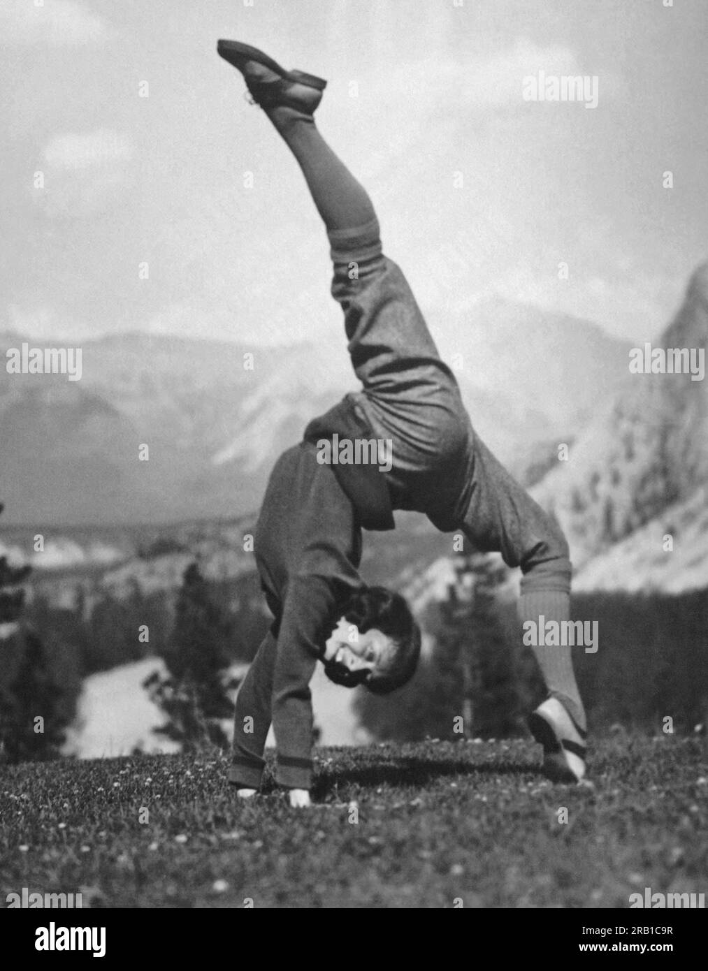 Bow Valley, Alberta, Kanada: 9. August 1923 Eine gelassene junge Frau macht einen Handstand mit den Spalten auf einer Wiese in den Kanadischen Rockies. Stockfoto