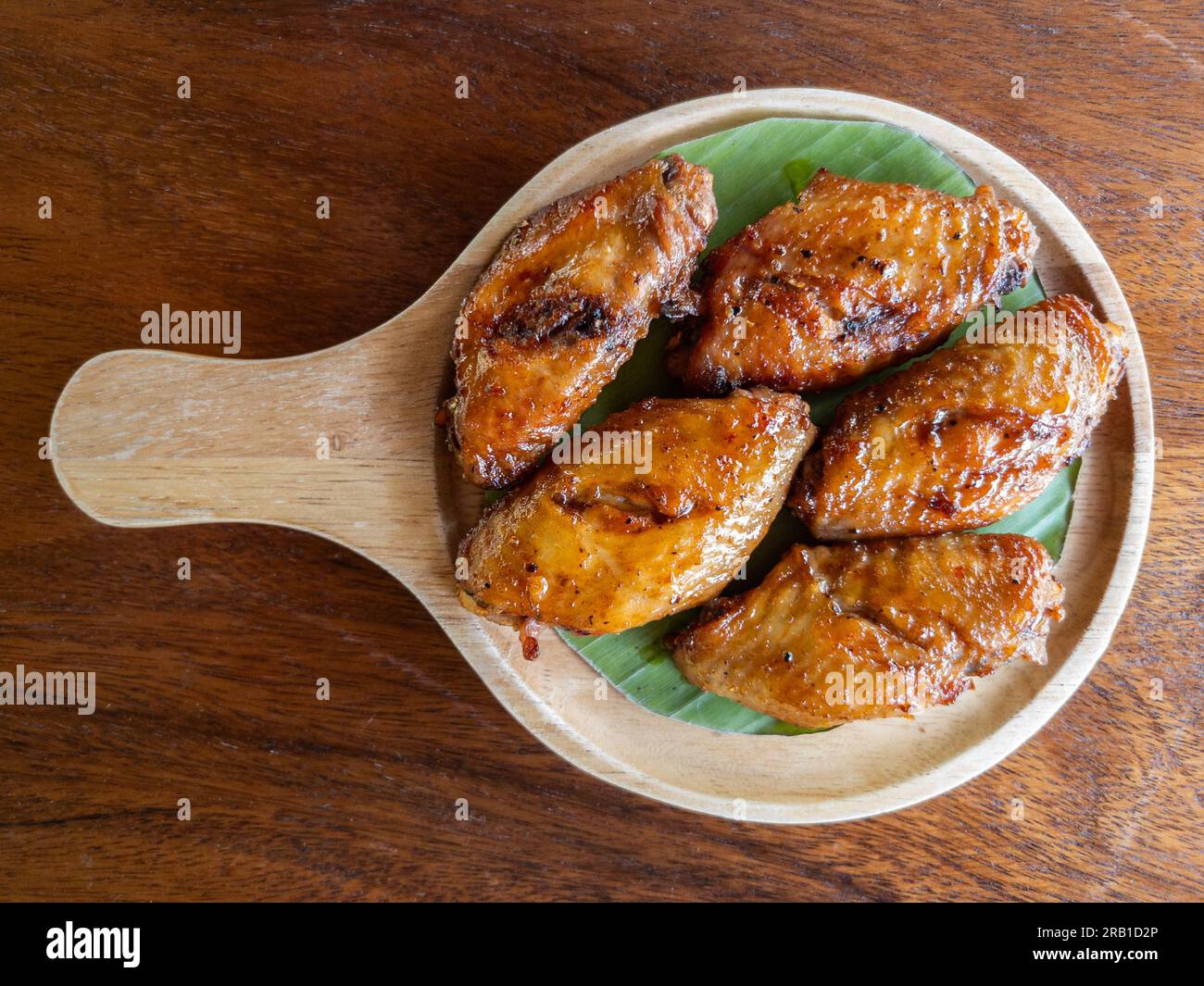 Die gebackenen Chicken Wings mit BBQ Sauce serviert auf einem Holzteller in dem kleinen Restaurant, Vorderansicht mit Kopierbereich. Stockfoto