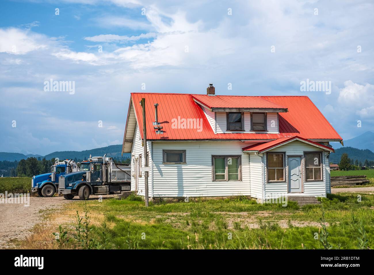 Nordamerikanische Farm Landhaus auf dem Feld. Auf dem Land Kanadas. Ländliches Bauernhaus mit Scheunen an einem sonnigen Tag im Sommer. Stockfoto