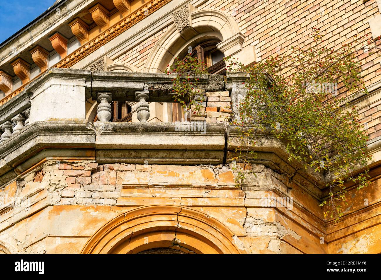 Verlassene, verfallene, orange Landhaus in der Nachmittagssonne mit verfallenem Balkon und kaputten Fenstern Stockfoto