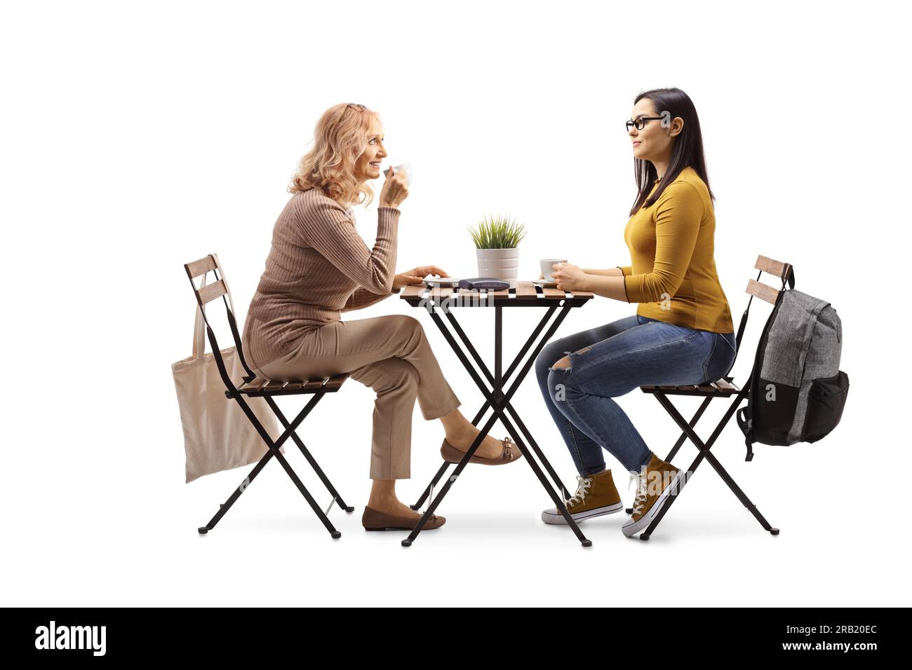 Reife Frau und eine Studentin, die an einem Tisch sitzt und Kaffee trinkt, isoliert auf weißem Hintergrund Stockfoto