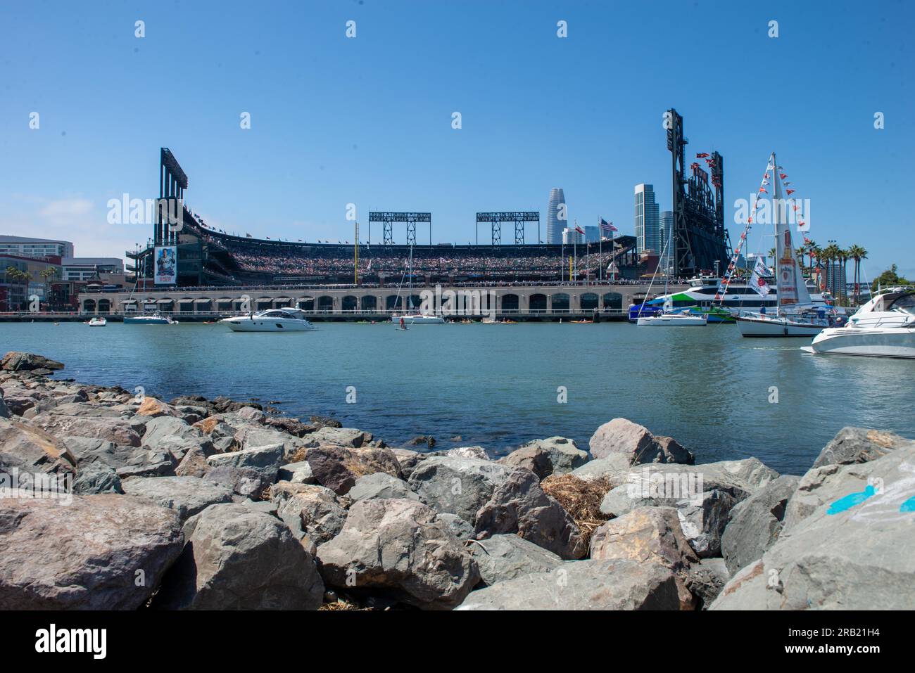 Fans besuchen ein Major League Baseball-Spiel im Oracle Park, Heimstadion der San Francisco Giants, San Francisco, Kalifornien, 4. Juli 2023, Der Oracle Park bietet einen Blick auf McCovey Cove, wo sich Gelegenheitsboote und Kajakfahrer in der Nähe des Stadions sonnen, um Homerun-Baseballs zu sehen, die außerhalb des Parks zu sehen sind. Während des Gesangs der Nationalhymne, die eine US-amerikanische enthielt, fand eine Überführung statt Air Force HH-60G Pave Hawk Hubschrauber vom 129. Rescue Wing, Moffett Air National Guard Base, in Mountain View, Kalifornien, schwebt über dem Feld. An Feiertagen und bei besonderen Veranstaltungen zu Ehren der C. Stockfoto