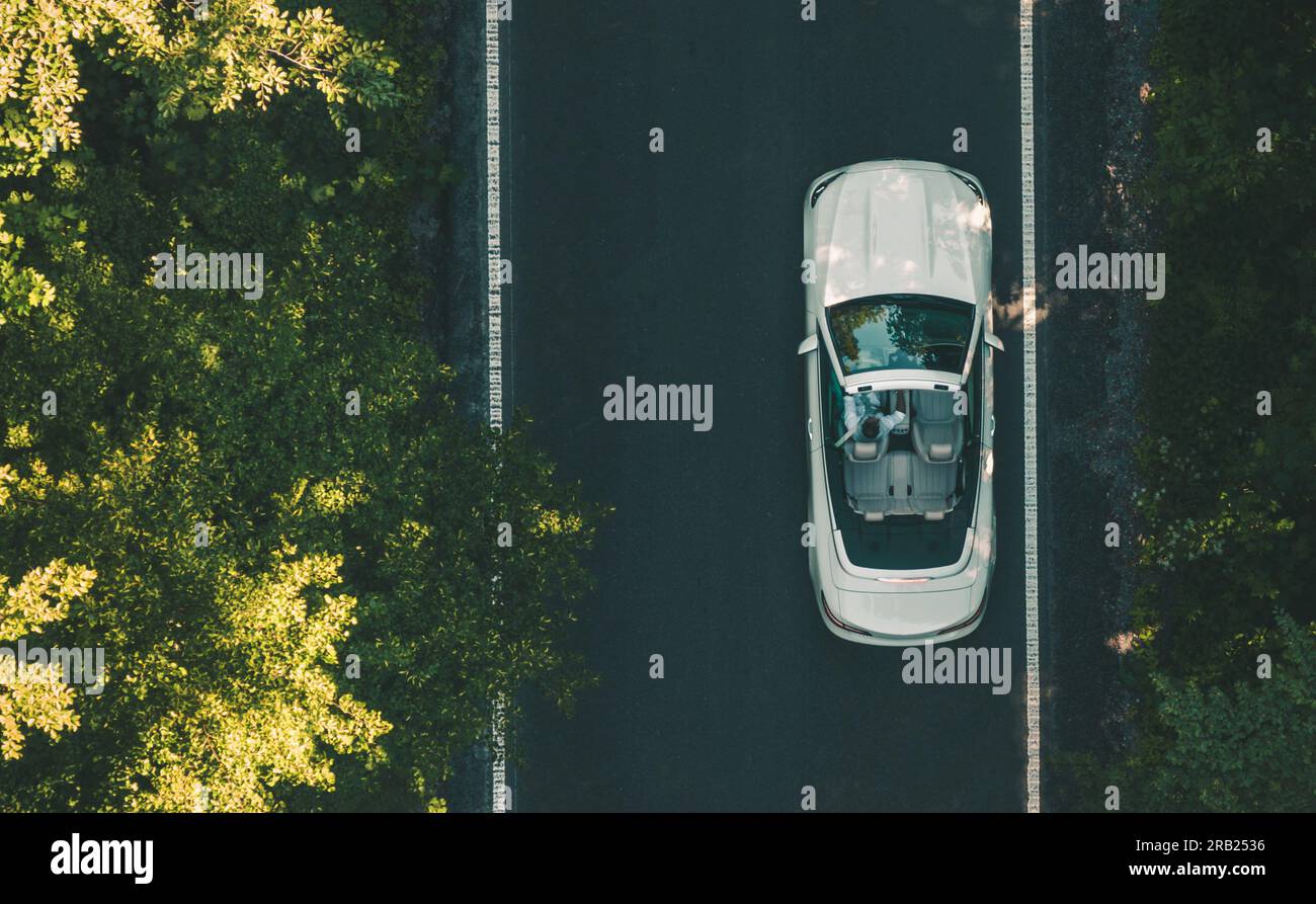 Luftaufnahme des Menschen, der sein modernes weißes Cabriolet entlang der Straße fährt. Luxuriöses Lifestyle-Thema. Stockfoto