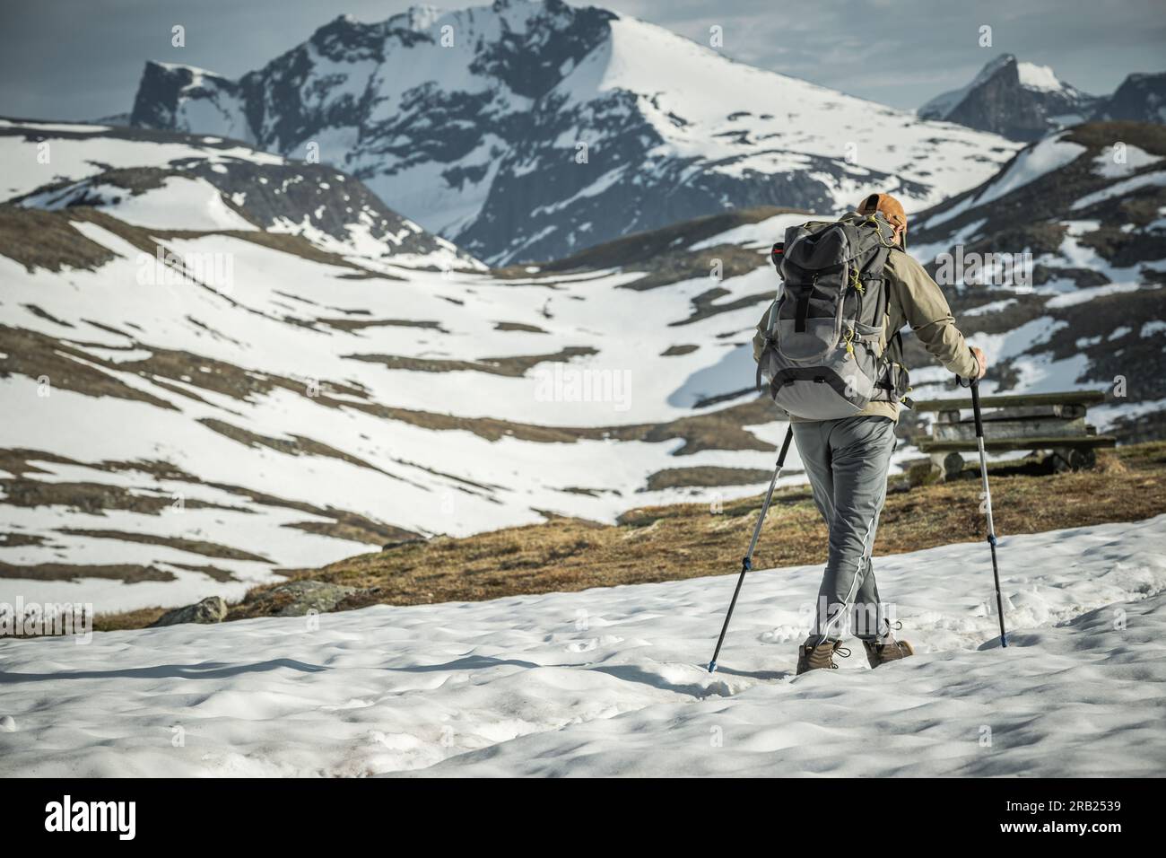 Rückansicht eines professionell ausgestatteten Touristen mit Rucksack und Wanderstöcken Wandern in den verschneiten norwegischen Bergen. Freizeitaktivitäten Im Freien Stockfoto