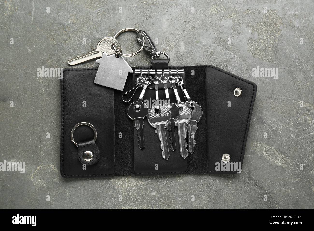 Eleganter Lederhalter mit Tasten auf grauem strukturiertem Tisch, Draufsicht Stockfoto