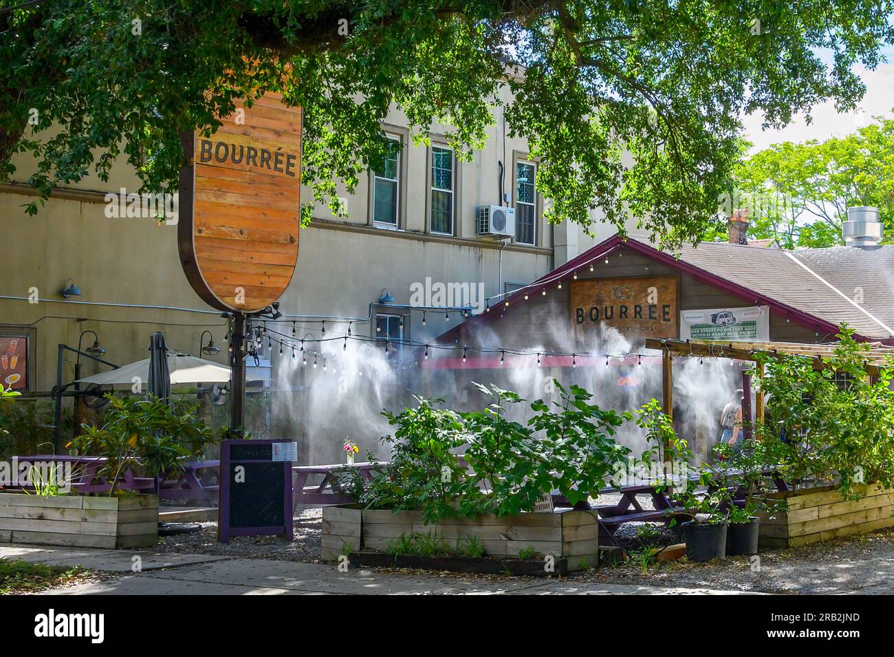 NEW ORLEANS, LA, USA - 5. JULI 2023: Bourrée Cajun Smokehouse mit Wassernebelsystem, das an einem heißen Tag im Außenbereich sprüht Stockfoto