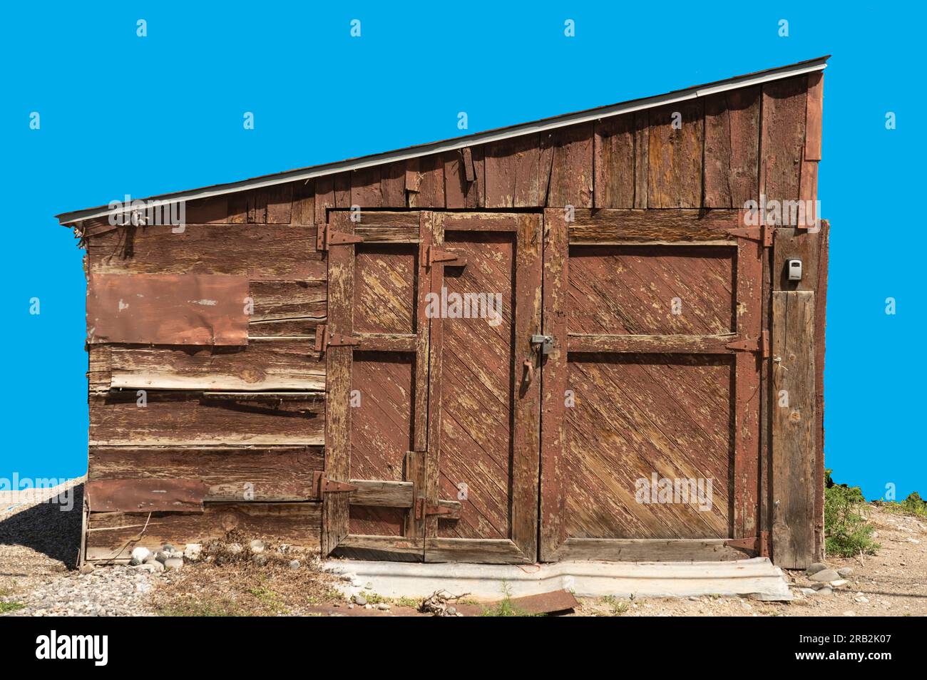 Nahaufnahme einer isolierten Scheune oder Hütte mit verwittertem Holz zeigt Flecken, Abdeckungen und Rahmen. Zusätzliche Holzrahmen hinzugefügt. Schrägdach ist ungewöhnlich. Stockfoto