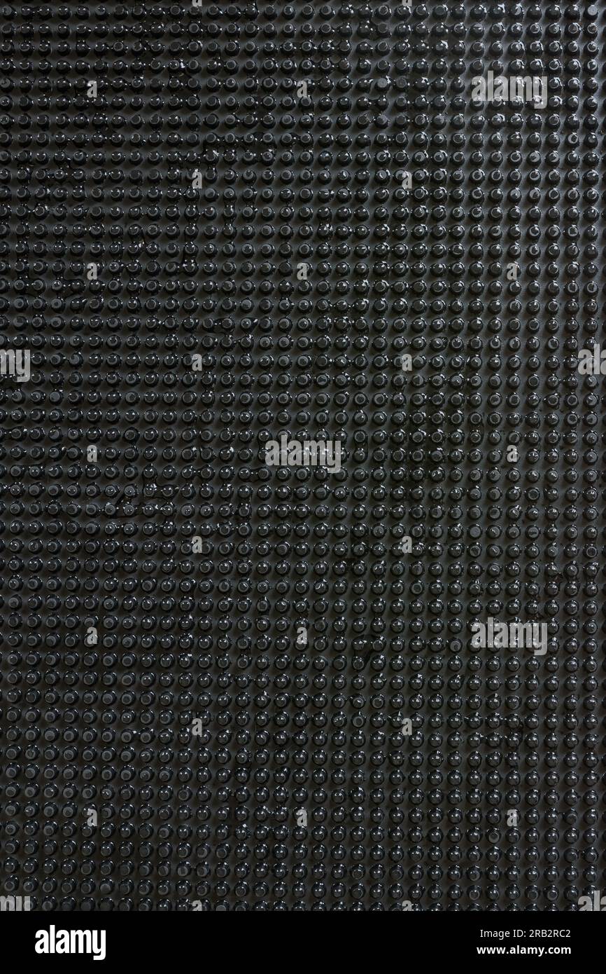 Abstraktes schwarzes Punktgitter im Hintergrund mit heller Wassertropfenbeleuchtung. Stockfoto