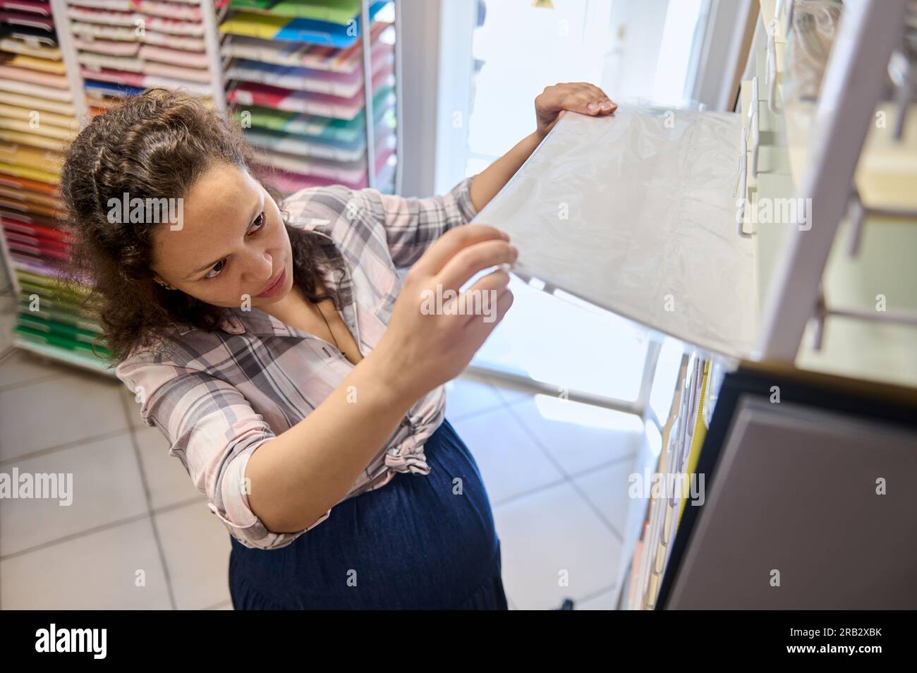 Draufsicht einer multiethnischen Verbraucherin, Künstlerin, Maler, Käuferin, die in einem Schreibwarengeschäft Aquarellpapier auswählt. Hobby und Beruf. Kleiner Bus Stockfoto