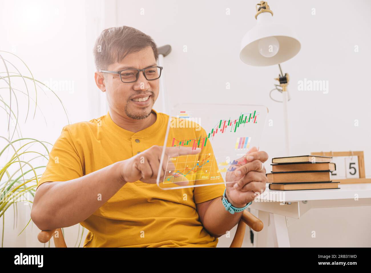 Ein glücklicher Geschäftsmann aus Südostasien, der auf eine Kapitalanlagekarte schaut, ein legerer Urlaub zu Hause Stockfoto