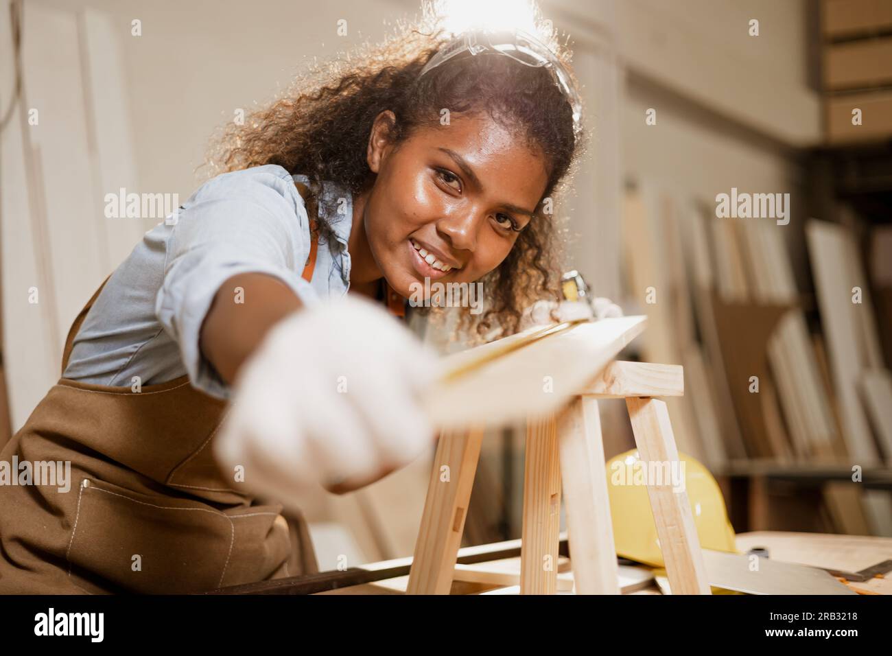 Afrikanische schwarze Frau, die mit Holzbrettdesign Heimmöbeln in einer Studiowerkstatt arbeitet. Stockfoto