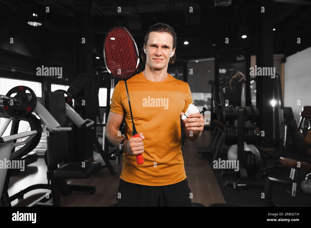 Cleverer professioneller Badminton-Spieler mit Schläger und Federn-Shuttle Stehporträt im Fitnessstudio, Sportclub, Muskeltraining Stockfoto