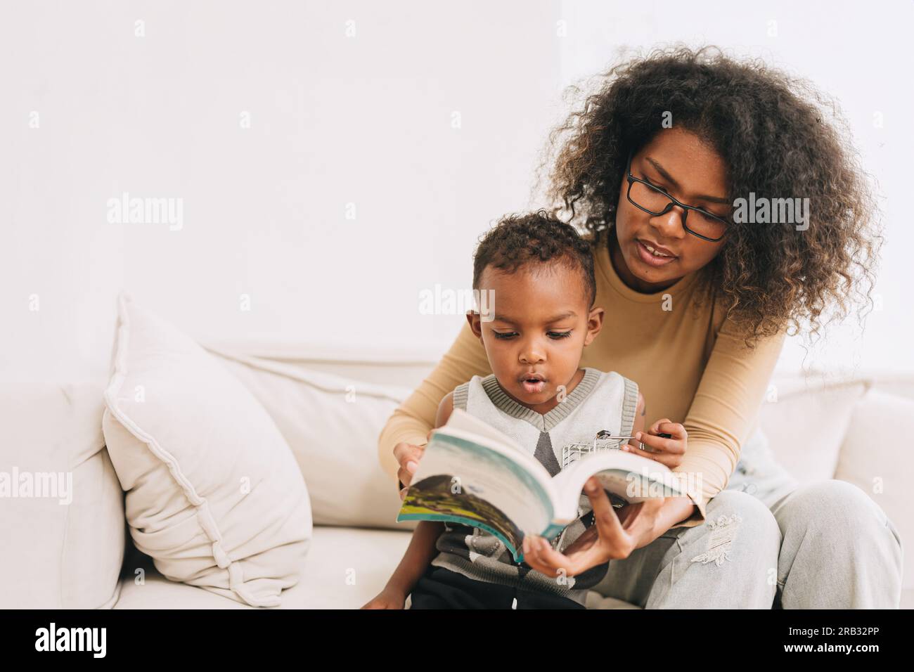 Erziehungsmutter, die dem kleinen Jungen etwas beibringt interessant, das Buch für den klugen Jungen zu lesen, afrikanische Schwarze Familie Stockfoto