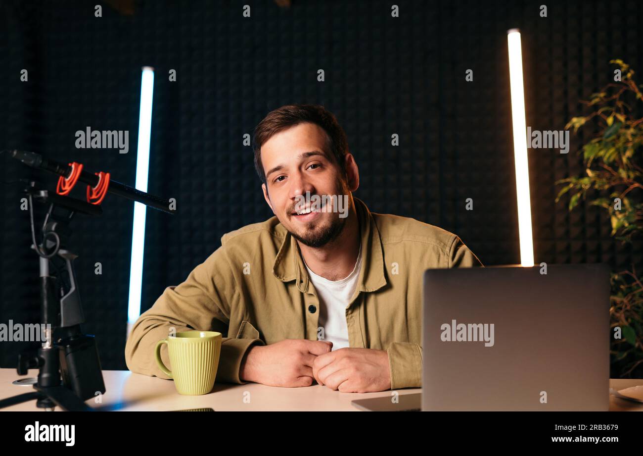 Ein lächelnder Radio-Host in das Studio-Mikrofon eines Radiosenders mit Neonlichtern, die in die Kamera schauen Stockfoto