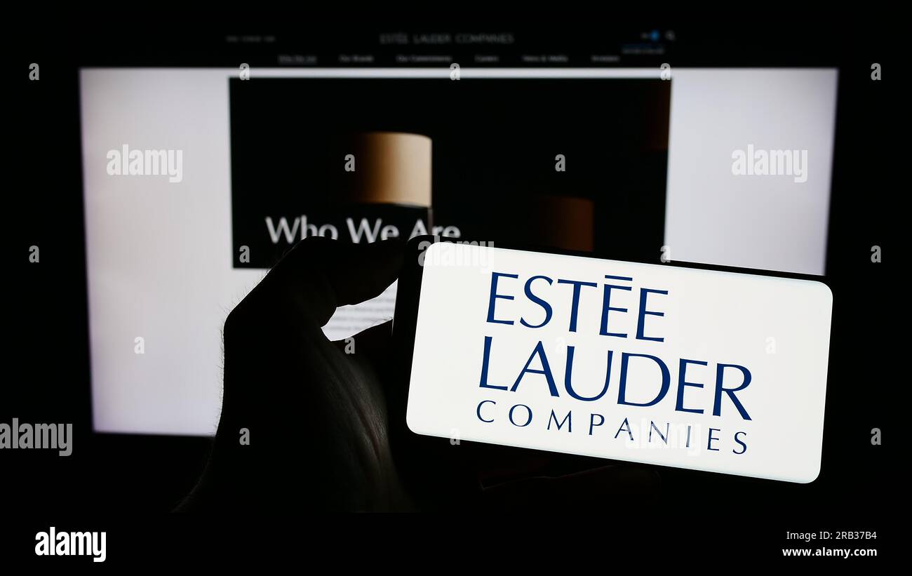 Person, die ein Mobiltelefon mit dem Logo des US-amerikanischen Unternehmens Estee Lauder Companies Inc. Auf dem Bildschirm vor der Unternehmenswebseite hält. Konzentrieren Sie sich auf das Display des Telefons. Stockfoto