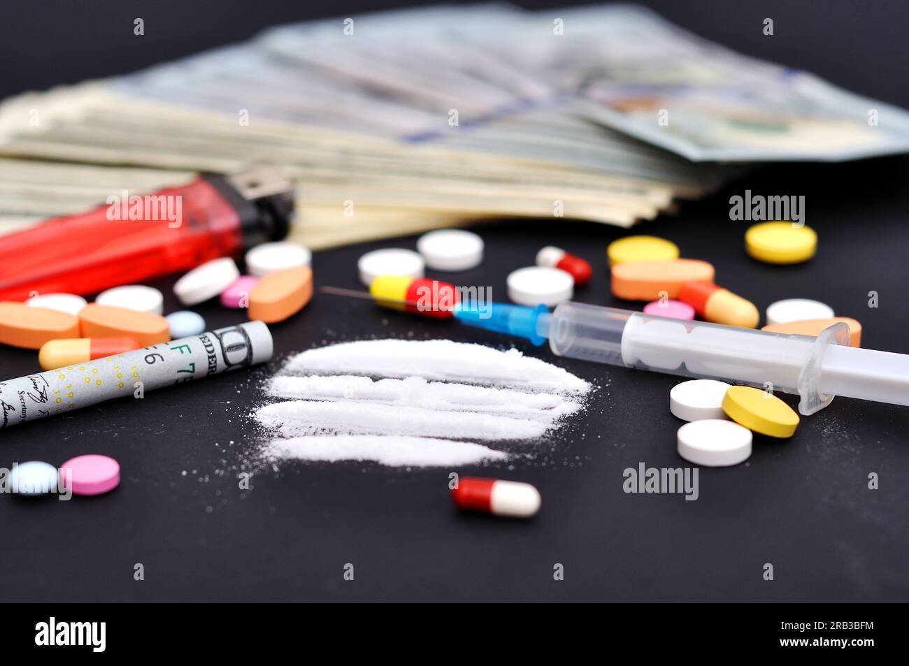Kokainlinien neben einem eingepackten Dollarschein und Rauschtabletten Stockfoto