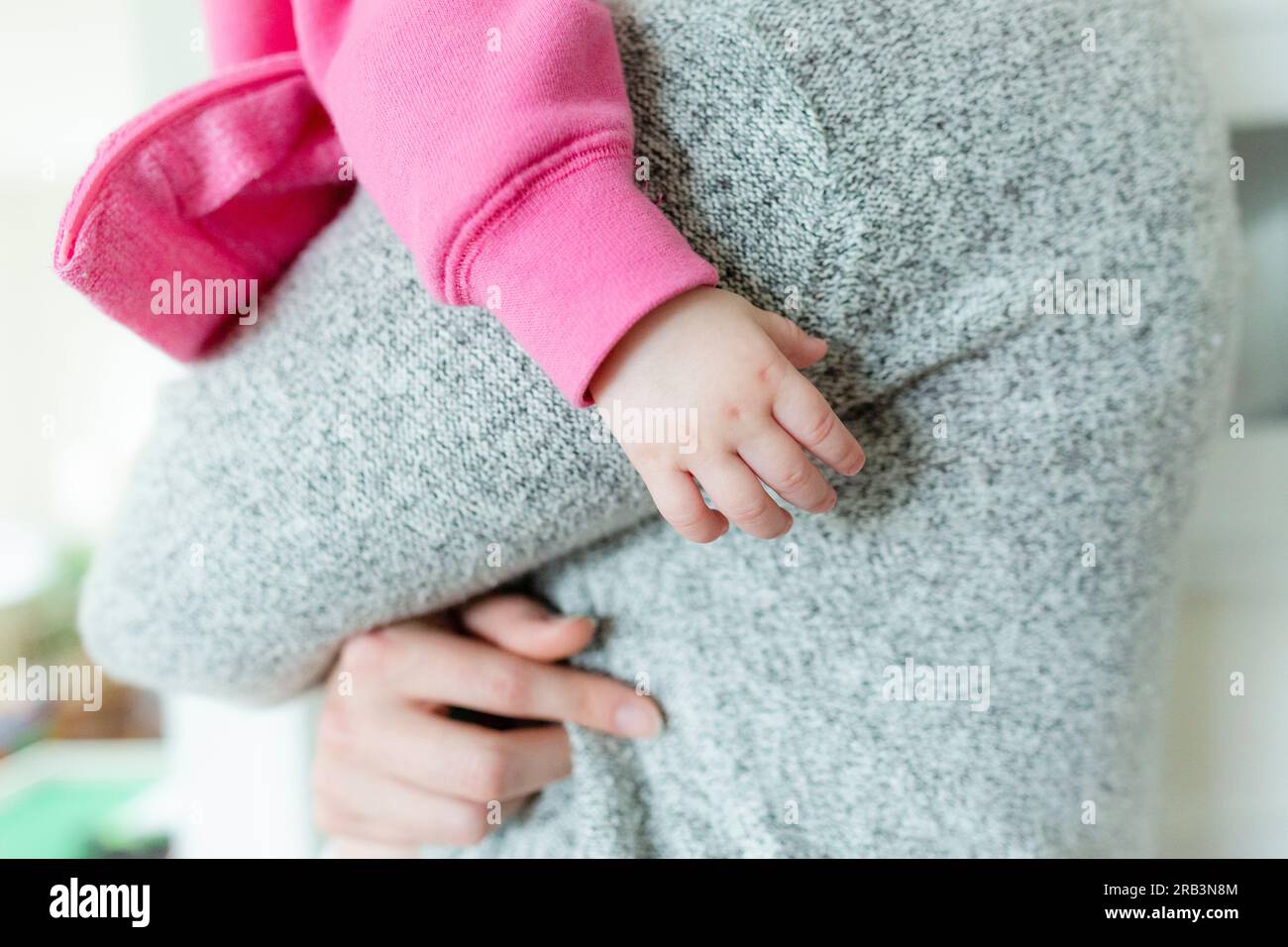 Nahaufnahme der Hand eines kleinen Mädchens, während sie in den Armen der Mutter gehalten wird Stockfoto