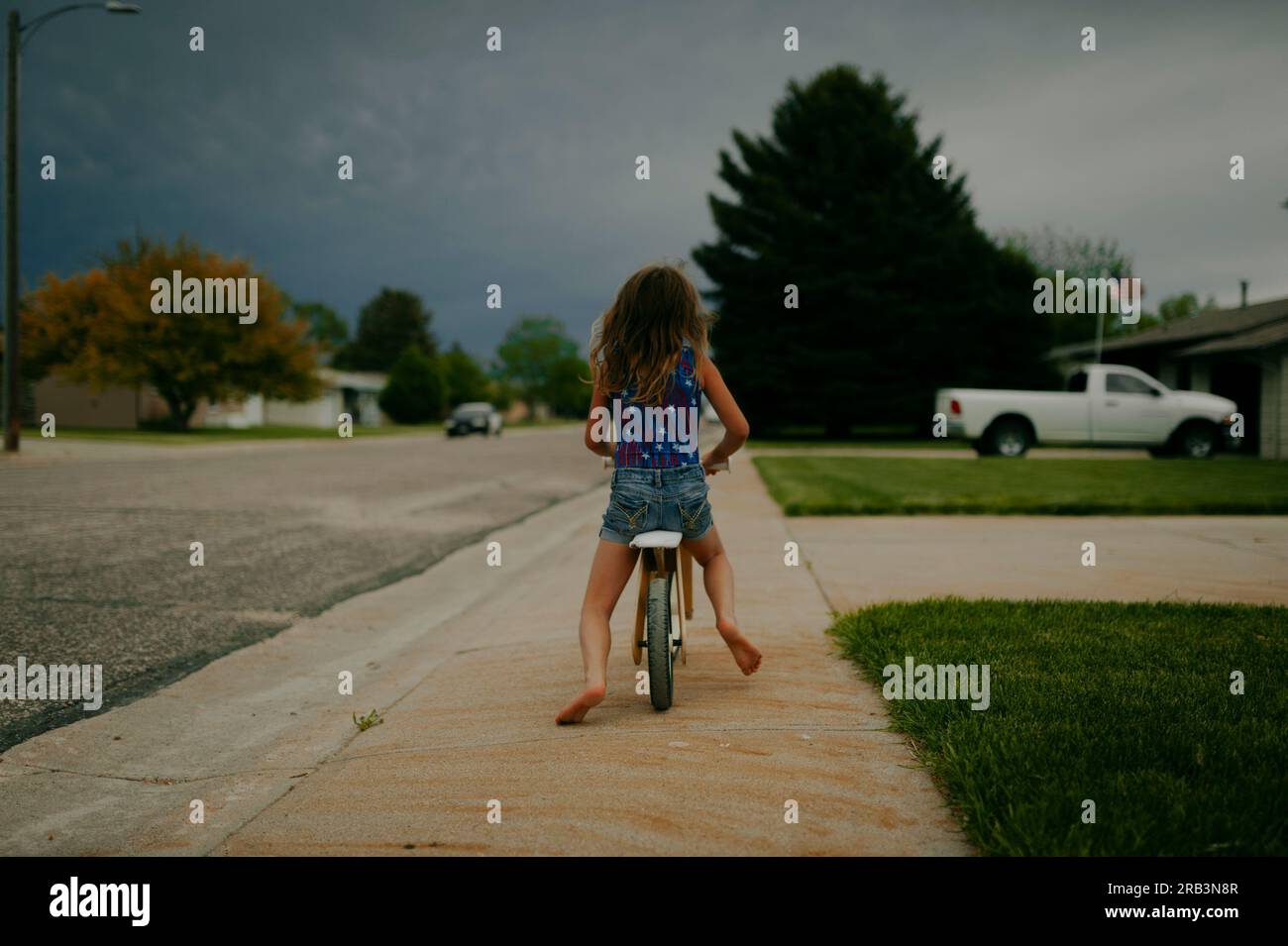 Mädchen, die Fahrrad fahren in stürmischer Sommernacht Stockfoto