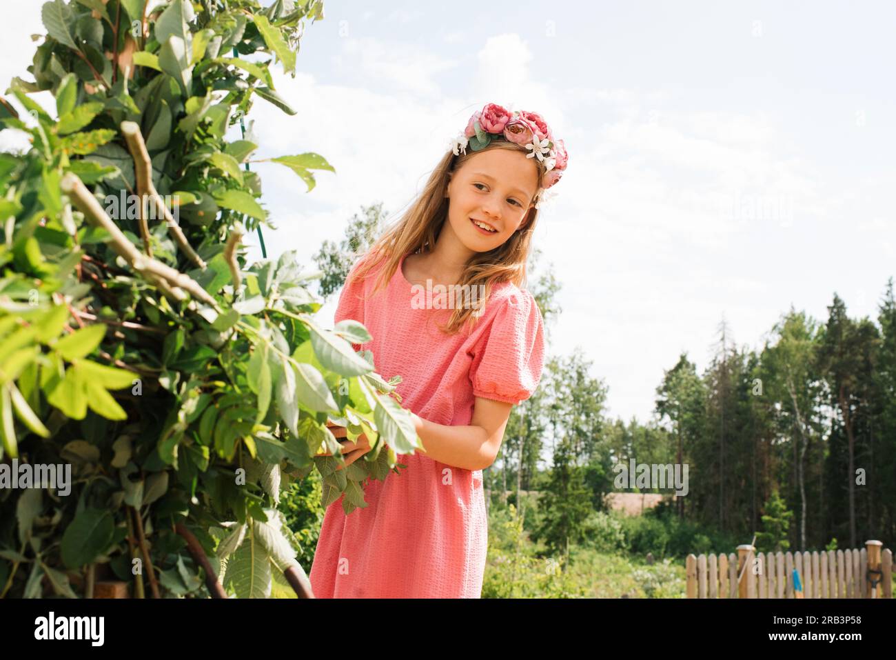 Ein junges Mädchen, das dabei hilft, die Mittelsommerstange in Schweden zu dekorieren Stockfoto
