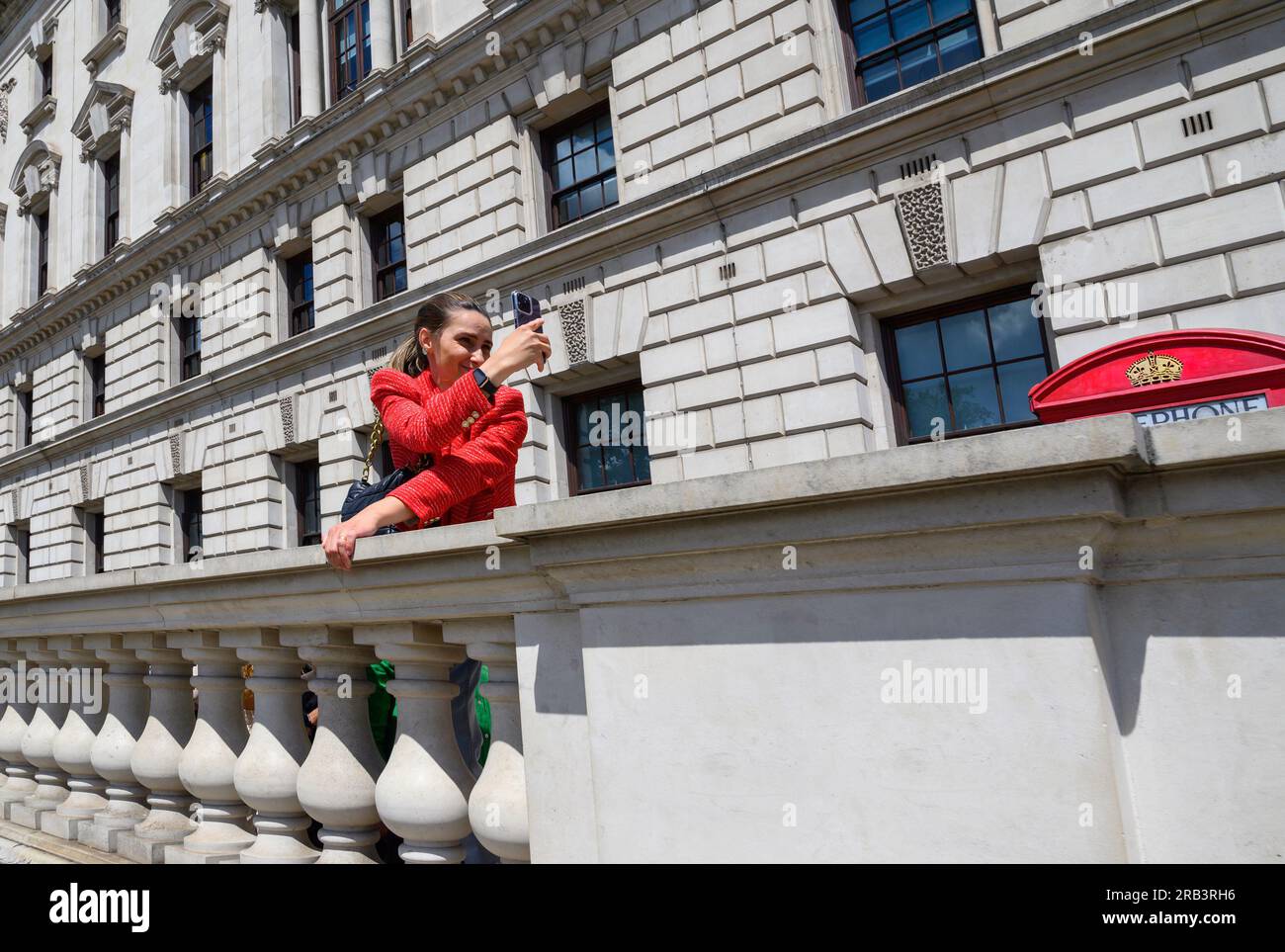 London, Großbritannien. Junge Frau in Rot, die ein Selfie auf dem Parlamentsplatz in Westminster macht Stockfoto
